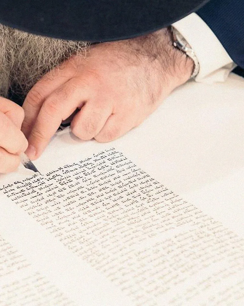 A hand writing a letter with a dip pen.