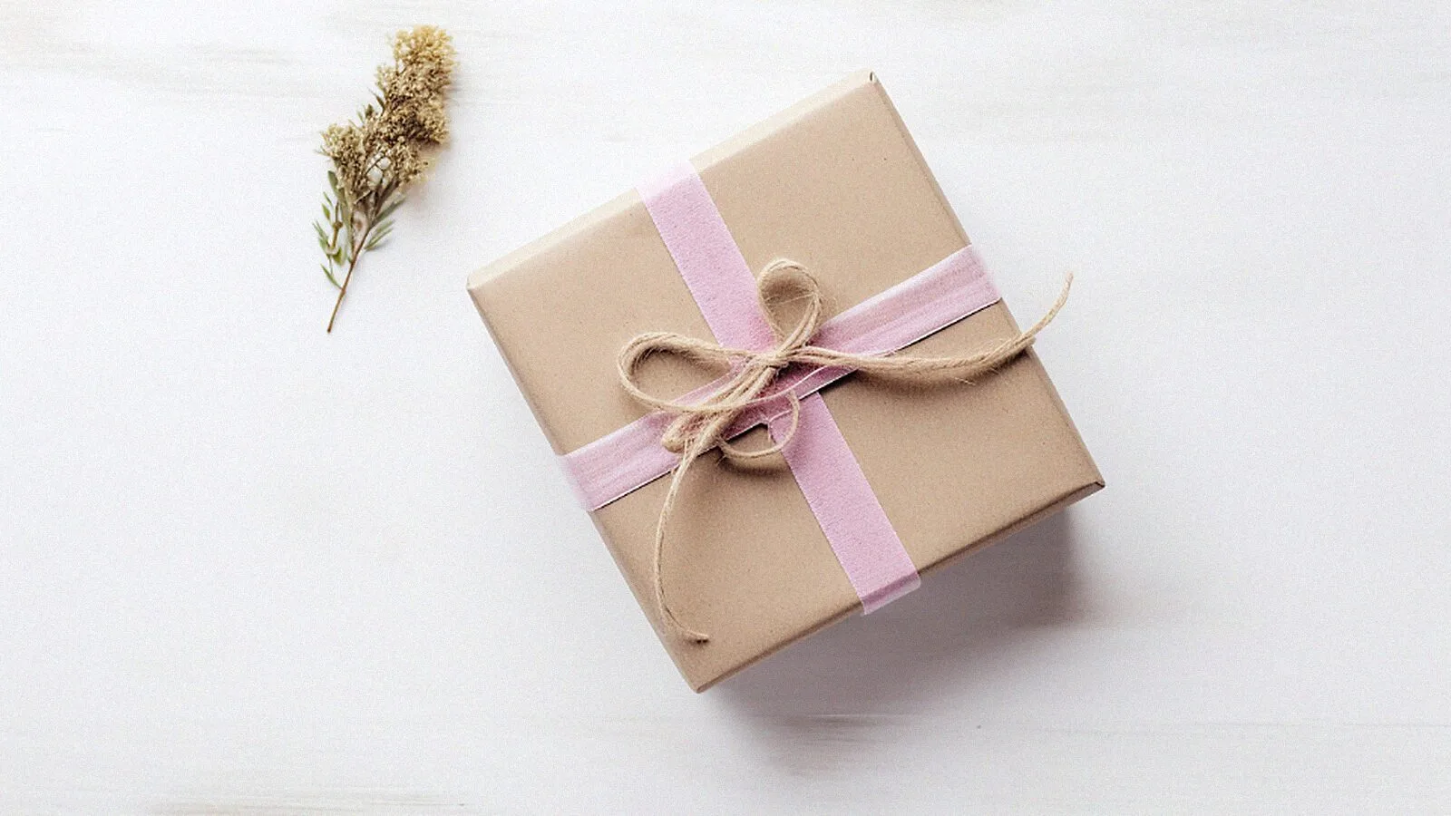 A kraft paper box tied with pale ribbon on a white table.
