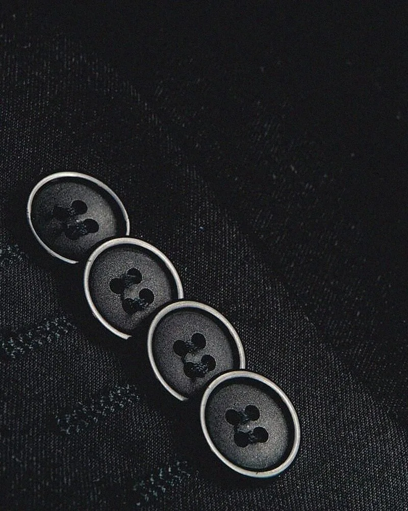 Four horn buttons on a charcoal suit cuff.