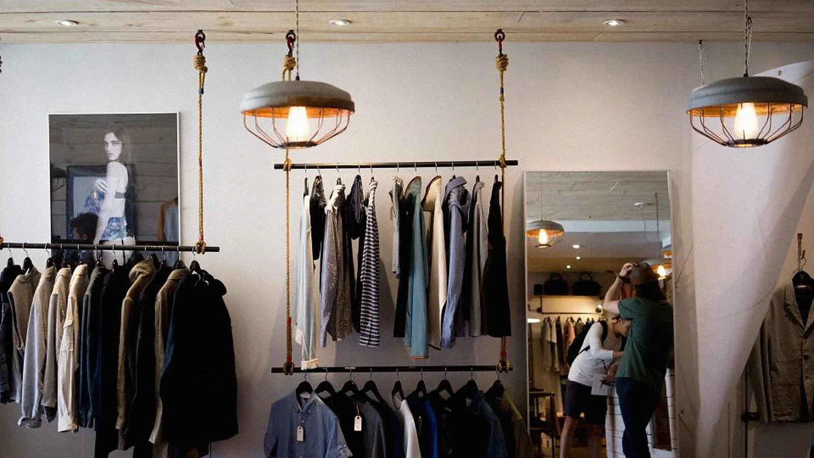 A quiet clothing rail under pendant lamps in a small shop.